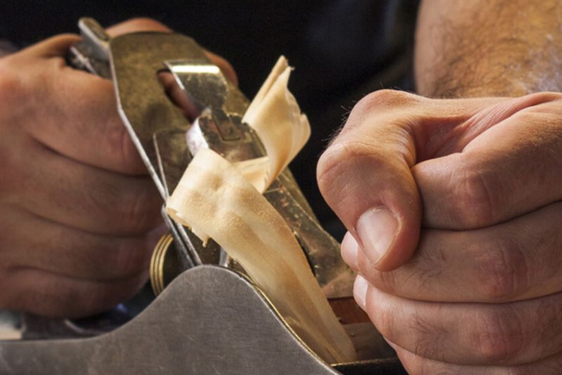 Hand hält eine Holzpfeile und schleift Holz